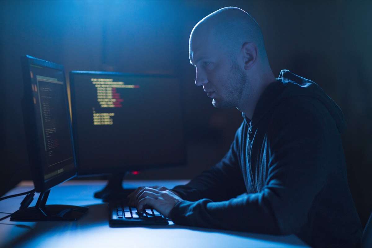 A security researcher working at a laptop with lines of code on the screen