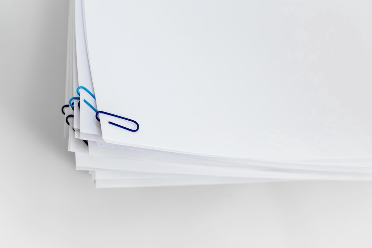 A stack of paper documents beside a rubber approval stamp on a desk.