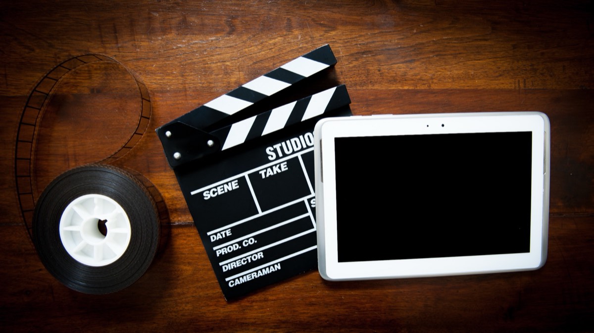 A film clapperboard resting on stacked screenplay pages under low lighting