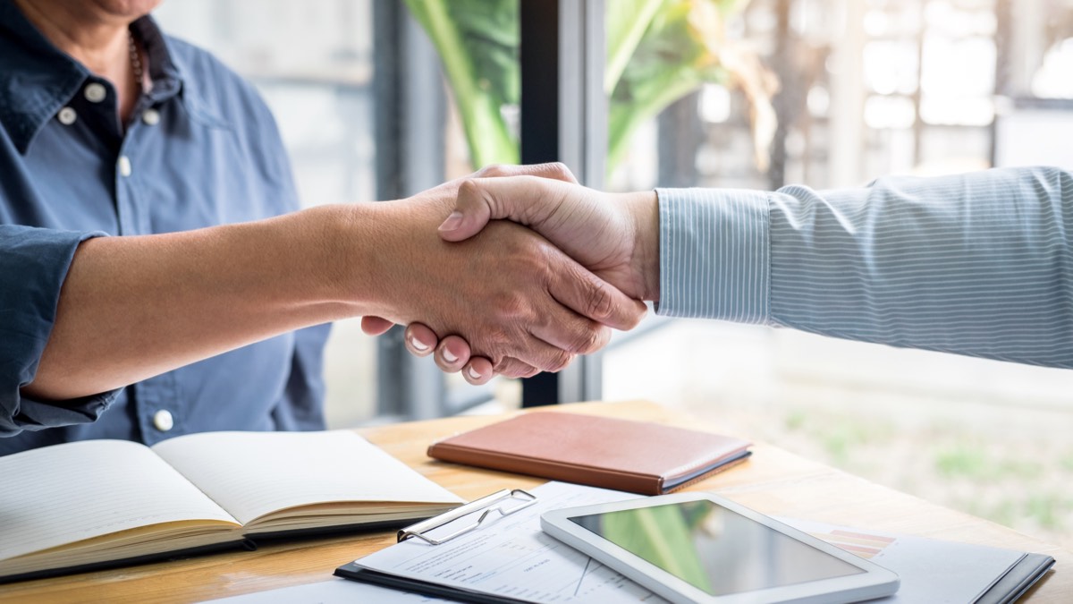 Two business people shaking hands over a patent licensing agreement and certificate