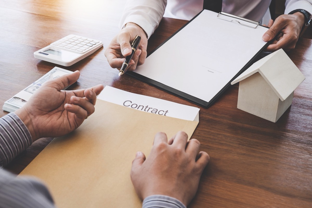 A person signing a confidentiality agreement with a pen on a desk