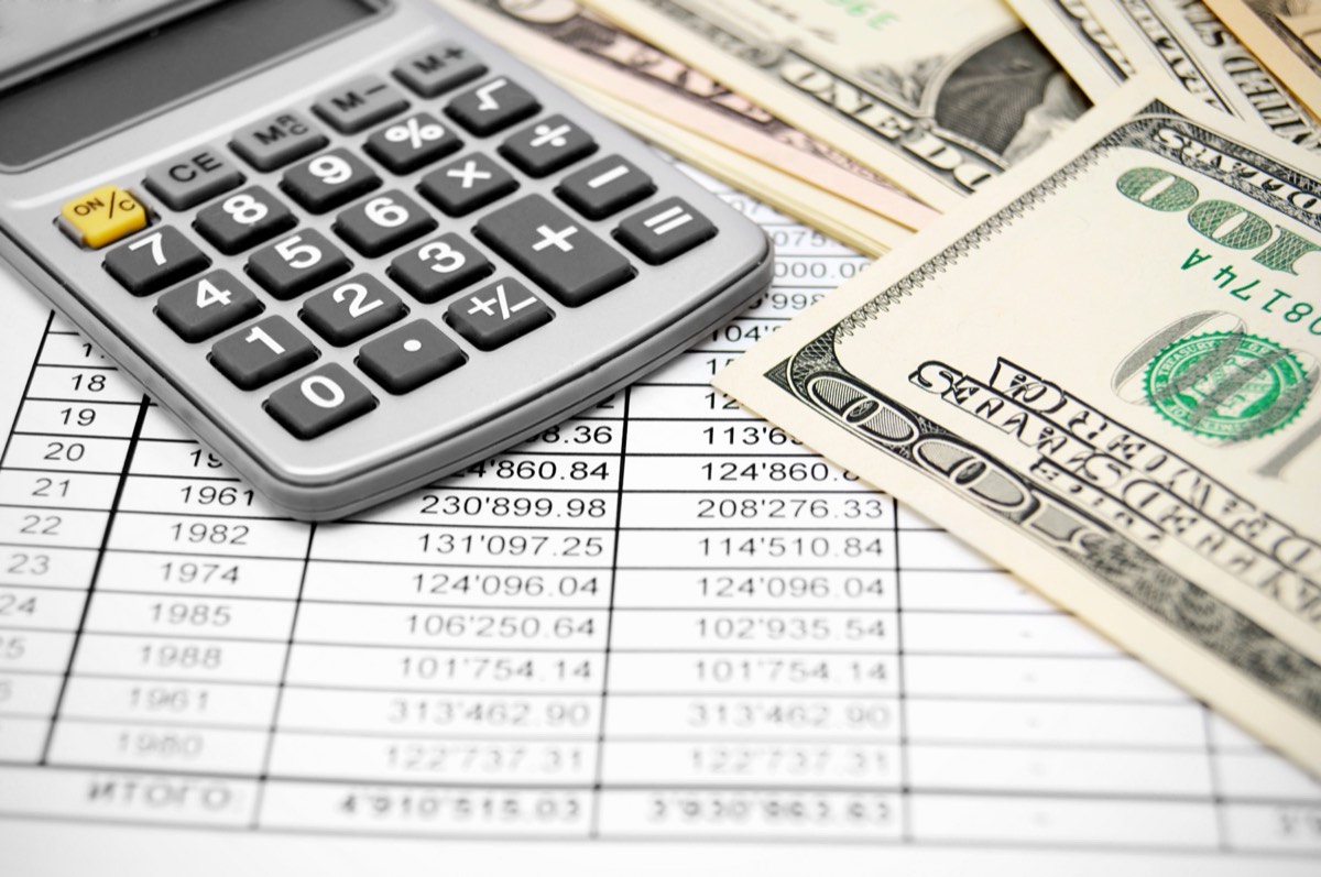 Small-business owner budgeting trademark costs at a desk with a calculator