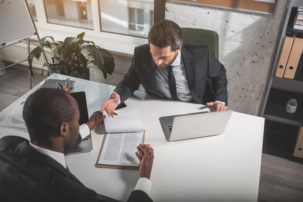 Two business people facing each other across a table in a tense meeting
