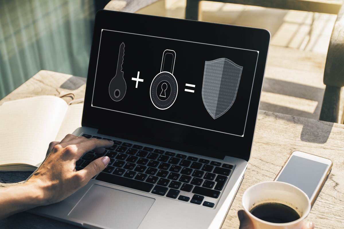 Hands typing on a laptop with a brand protection security overlay
