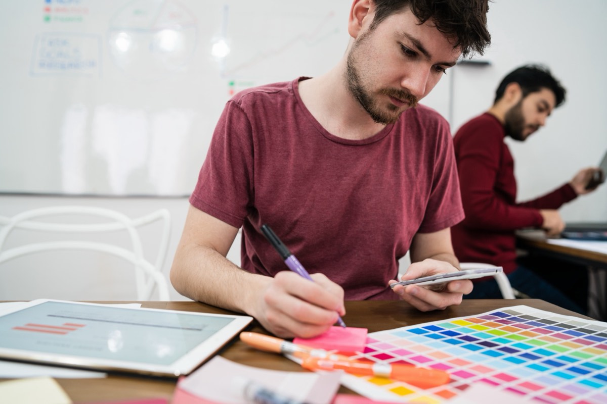 Freelance designer handing a finished logo design to a client at a laptop