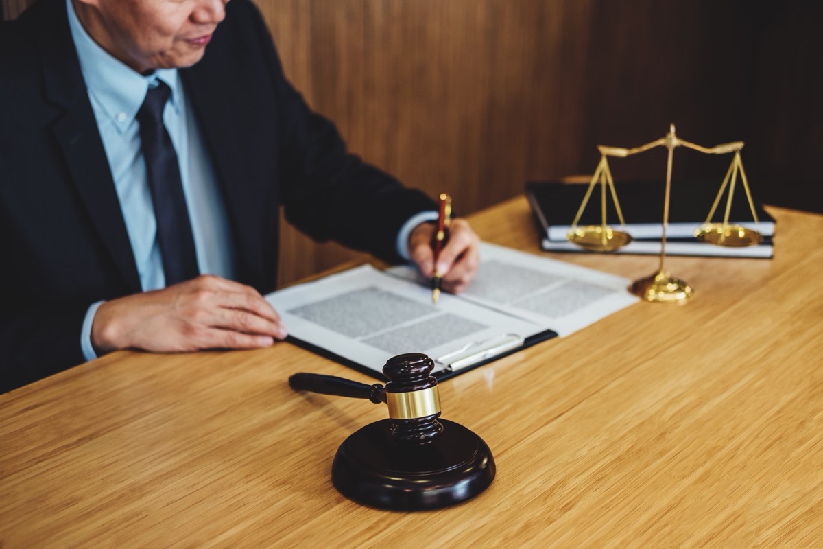 A judge's bench with a gavel and patent documents under a desk lamp
