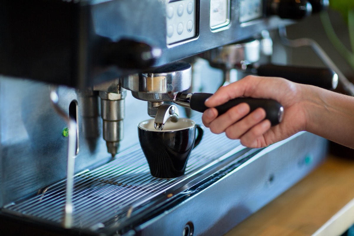 Coffee capsules on a machine tray beside an espresso cup