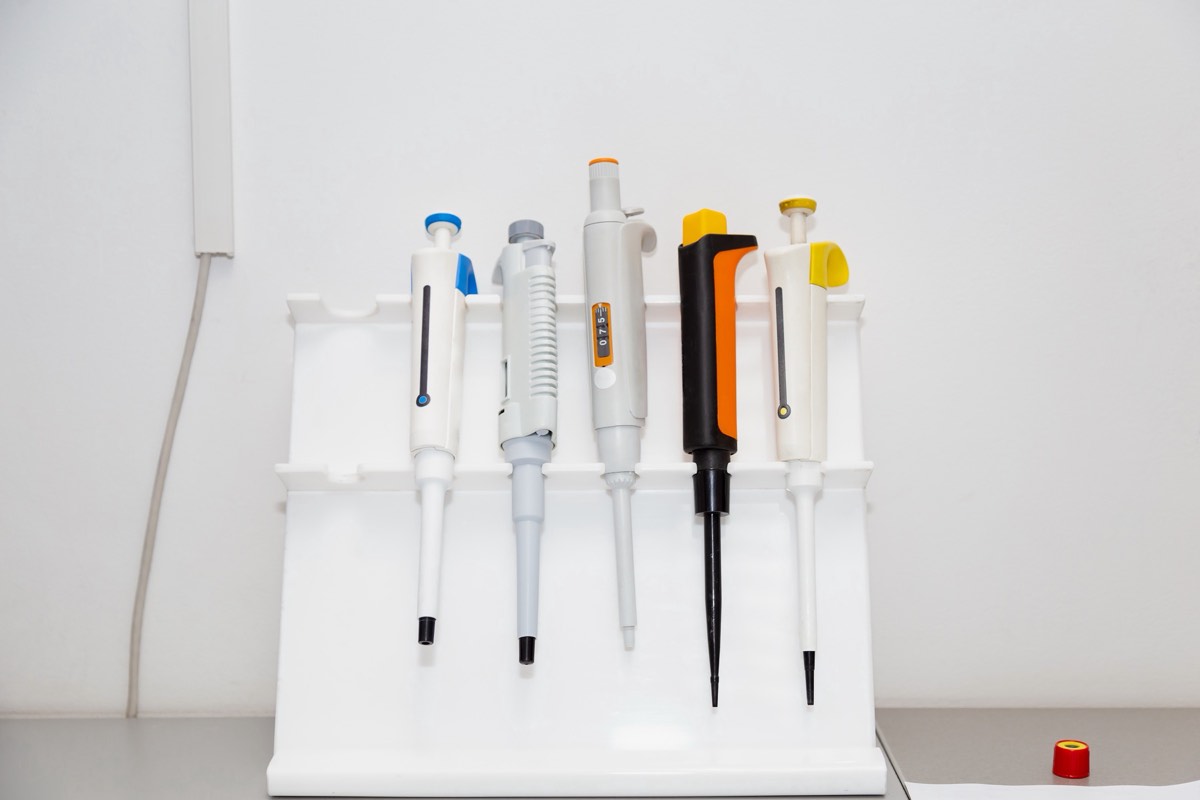 A laboratory researcher pipetting samples into a tray of vials