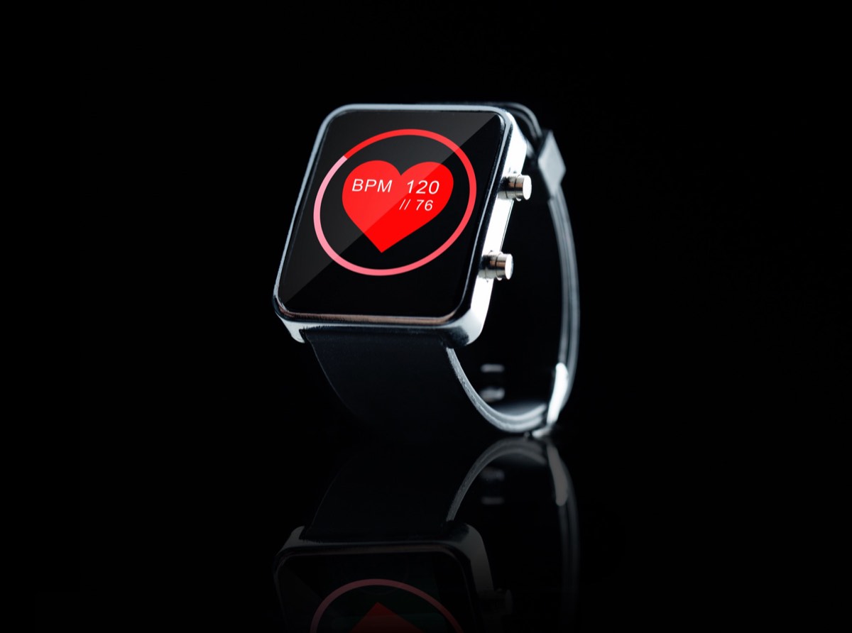 A smartwatch on a wrist with a green optical heart-rate sensor glowing on the underside
