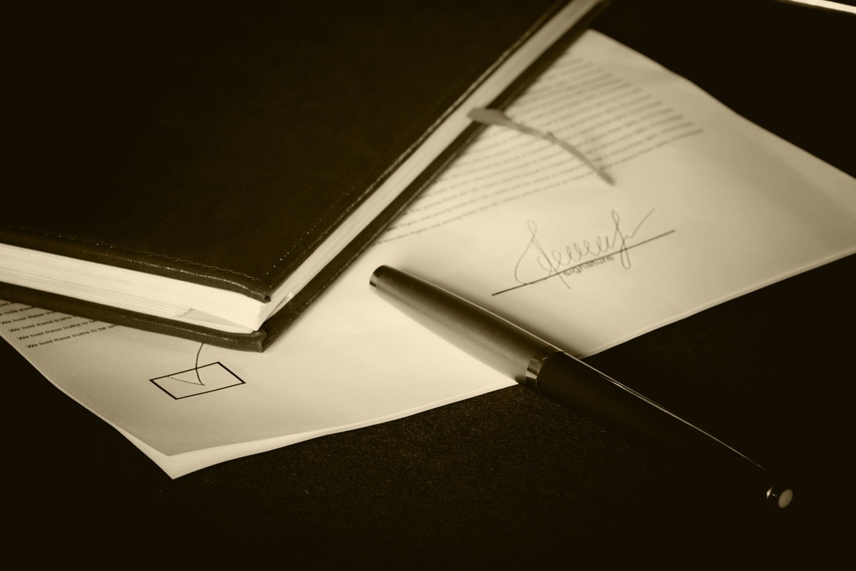 A close-up of a statute book open to text with a pen resting on the page