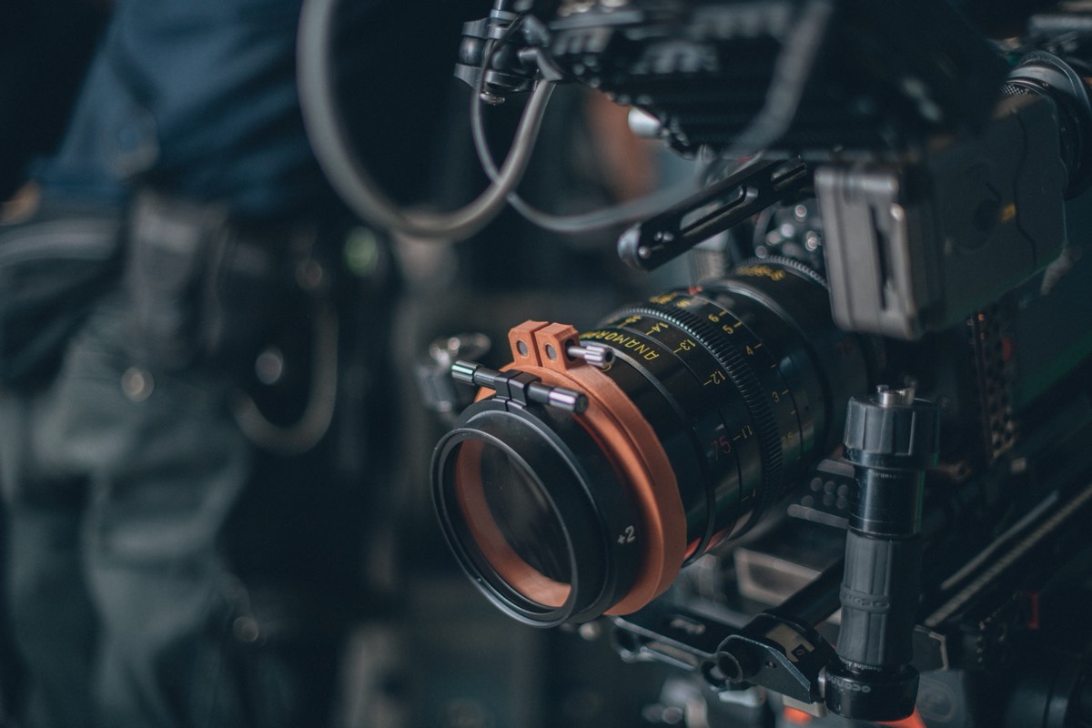 Film set with a camera crew shooting an outdoor scene at dusk