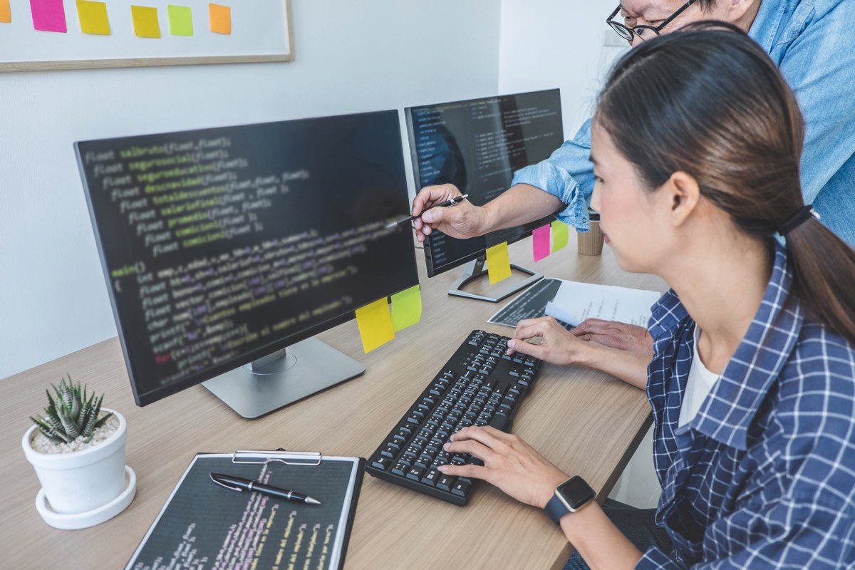 Developers reviewing source code on screens in a software office