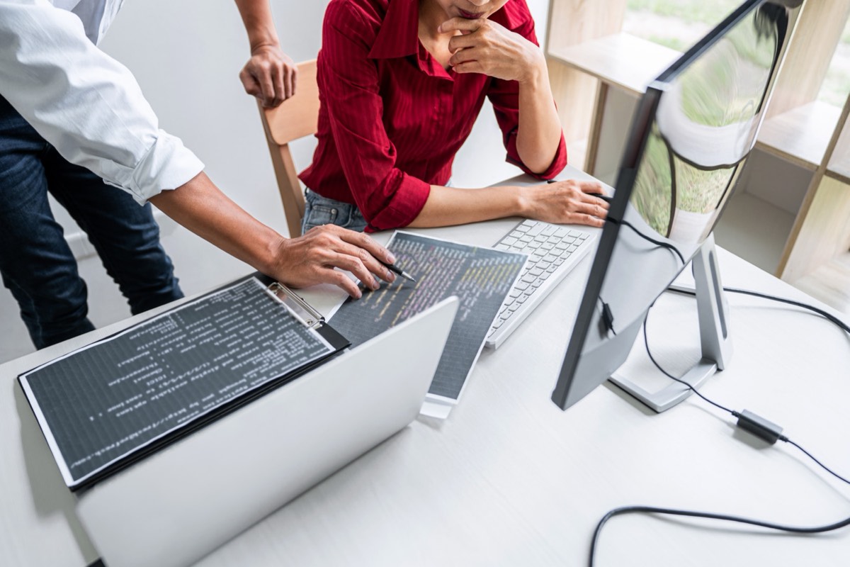 Software developers reviewing code on monitors in an office
