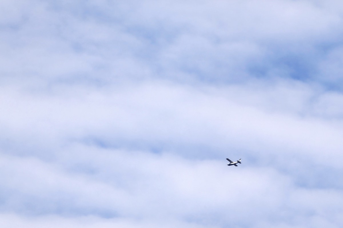 A small aircraft flying low over an industrial chemical plant