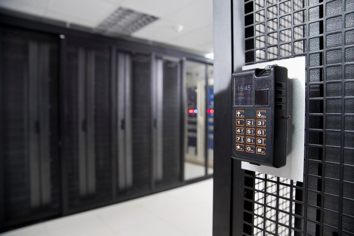 Server hard drives and a hand reaching toward a keyboard in a dim room