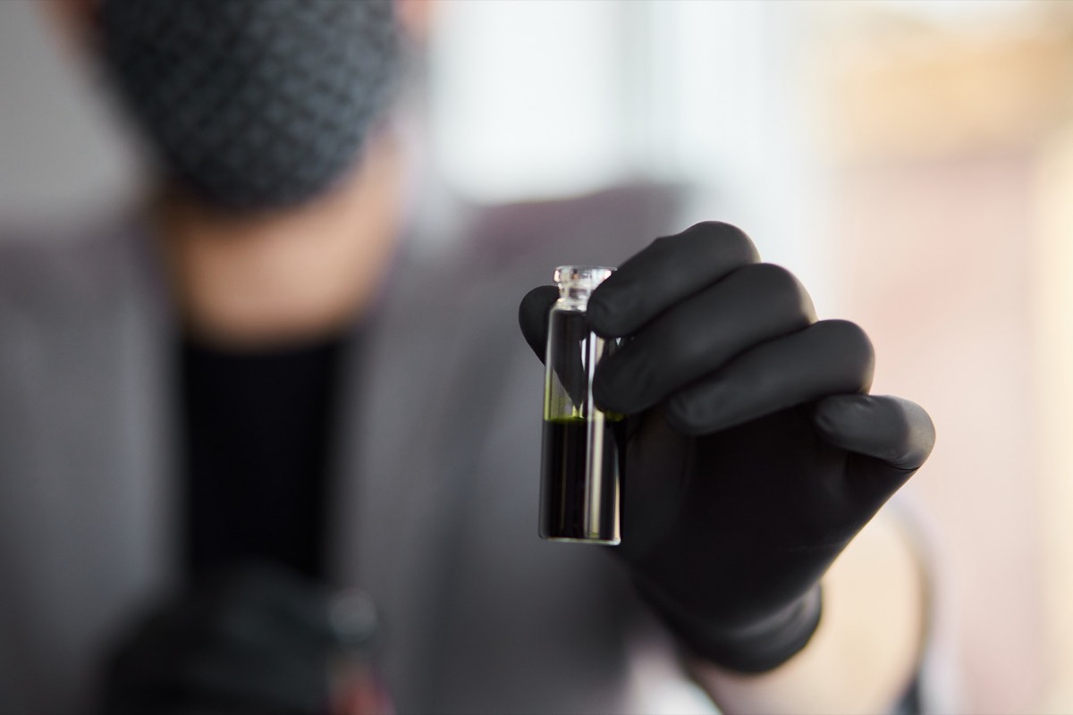A scientist's gloved hand holding a vial in a laboratory
