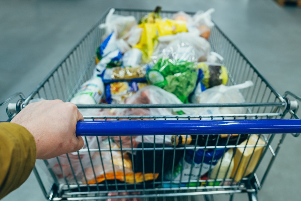 Grocery cart loaded with branded paper bags in a supermarket aisle
