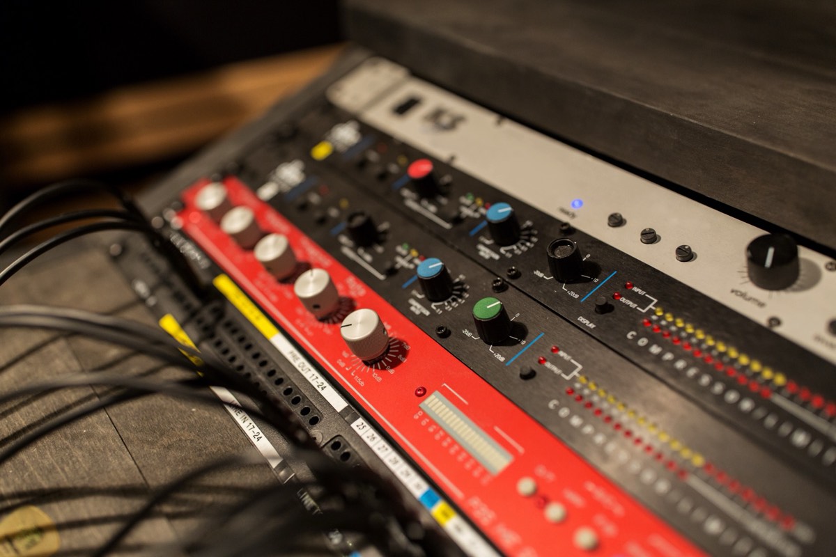 A recording studio mixing console with faders and a microphone