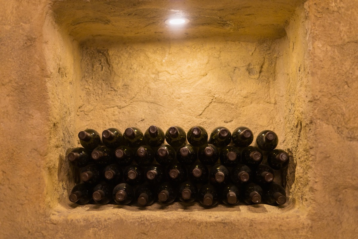 Rows of wine bottles aging on racks in a cellar