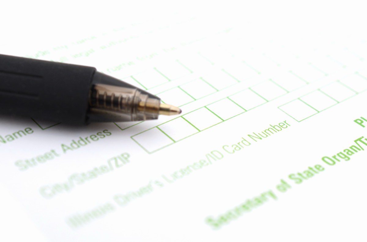A trademark application form on a desk beside a pen